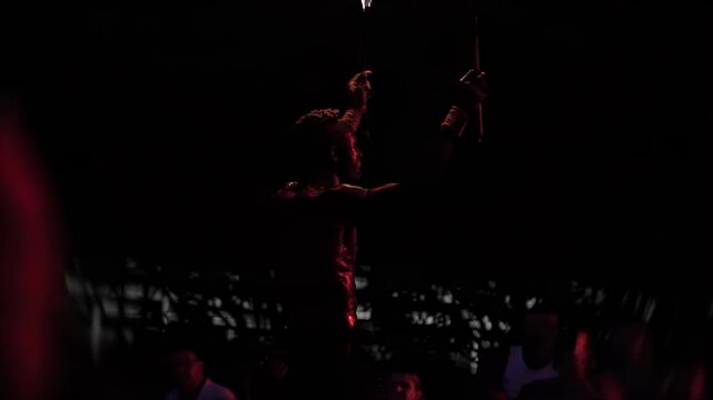 Captivating fire breathing performance by black man during night outdoor show, intense focus of performer, glowing fire illuminates face, dramatic water effect enhances visual appeal