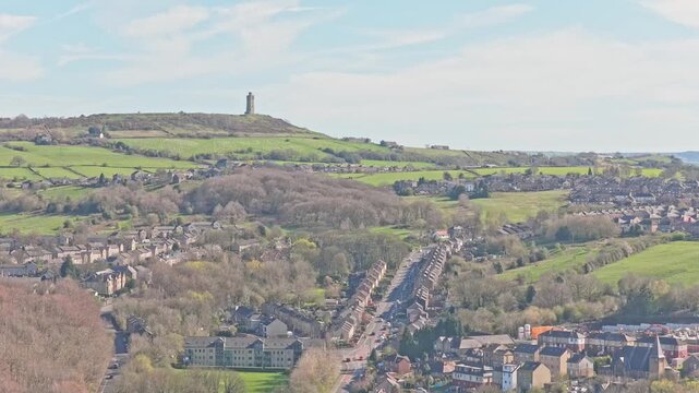 Castle Hill Victoria Tower overlooking Huddersfield in Kirklees West Yorkshire England United Kingdom with A629 Wakefield Road and terraced housing on hillside, drone descent aerial shot