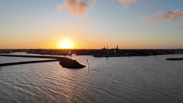 Forward dawn flight over quay toward harbor skyline