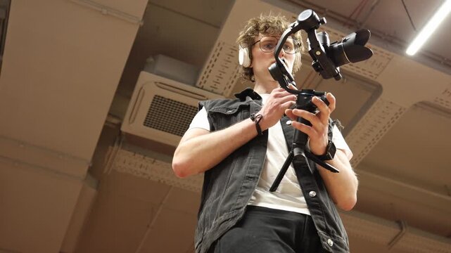 Videographer carefully adjusts gimbal balance and camera settings focusing on stability control and smooth motion preparing equipment for precise cinematic filming in professional indoor studio enviro