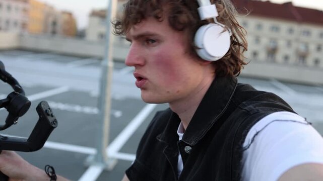 Videographer in headphones concentrates on camera control adjusting gimbal for smooth motion and accurate framing refining filming technique and building consistent professional shooting skills