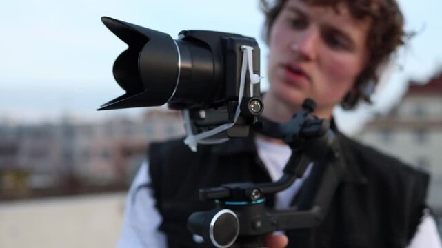 Beginner videographer awkwardly secures camera on stabilizer improvising setup and testing shot unstable gear creative learning process practice filming and hands on experience