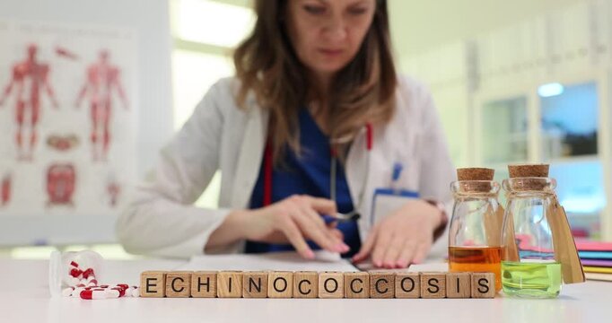Wooden blocks spell word Echinococcosis near medicine bottles and files. Doctor sorts records measuring doses while preparing lab referral forms