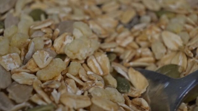 Extreme close up of a spoon scooping a mixture of granola and cereal grains