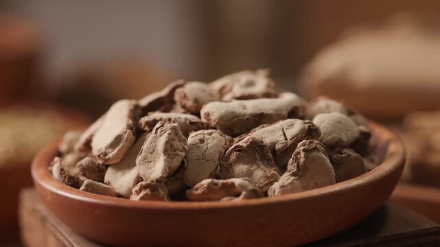 Rotating close-up of dried herbal root chunks with rough surface and irregular shapes. Natural texture highlights raw medicinal material in traditional herbal practice.
