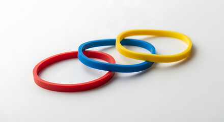 Fototapeta premium Three interlinked rubber bracelets in red, blue, and yellow on a white background