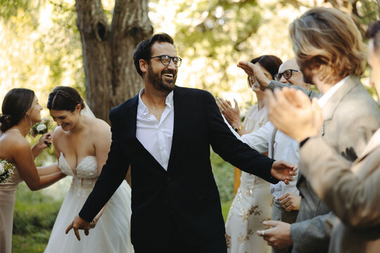 Groom celebrating with guests during outdoor wedding ceremony