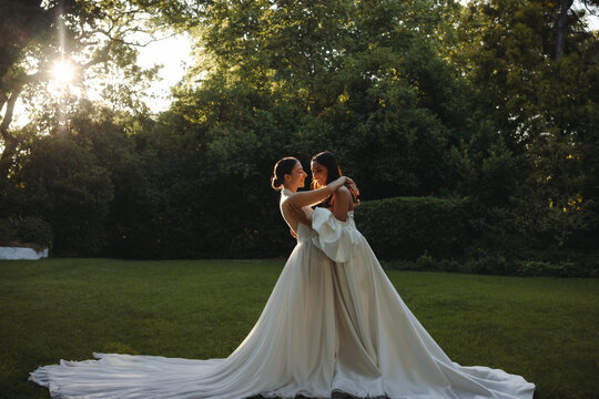 Romantic portrait of two brides embracing during an outdoor wedding ceremony