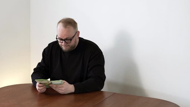 Man counts cash and shakes his head in worry, showing concern about not having enough funds, daily expenses, and real life financial pressure at home.