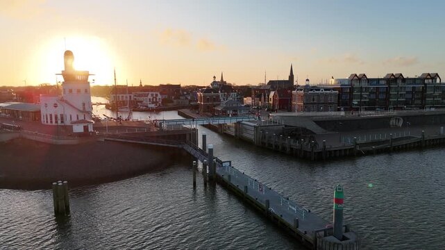 Sun threading behind round harbor building at dawn