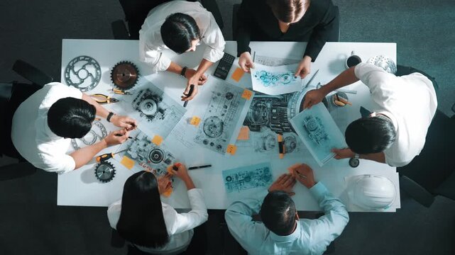 Top view of engineer pointing at turbine engine at meeting table with equipment. Aerial view of professional project manager talking and discussing about electronic generator system. Alimentation.