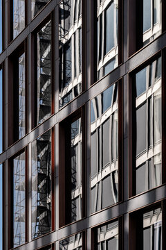 Glass windows reflect on a modern building facade where lines perspective and pattern create abstract architecture rhythm and strong reflection