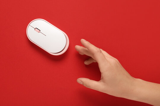 Female hand with modern wireless computer mouse on red background