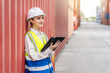 Obraz premium Professional female engineer or foreman using a digital tablet for checking inventory at a container cargo freight ship port. Logistics, supply chain, and transportation industry concept.