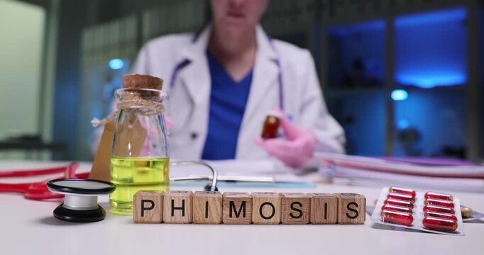 Word Phimosis on wooden cubes near drugs and stethoscope on doctor desk. Female physician holds pill bottle over medical records in hospital