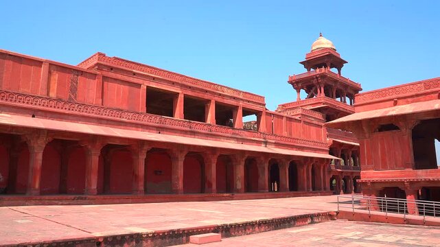 A panning shot highlighting the five-story Panch Mahal and the red sandstone architecture of the royal complex at Fatehpur Sikri under a clear blue sky.