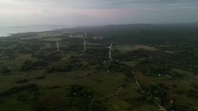 Wind turbines dot the landscape of Guimaras, set against a backdrop of gentle hills and distant coastline. Ideal for energy or environmental projects.