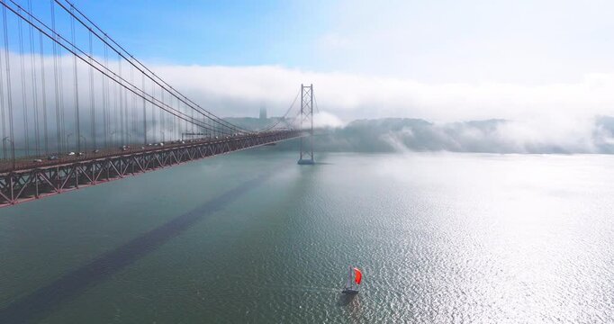 Drone establishing shot of the 25th April Bridge near Alcantara and Ajuda surrounded by fog