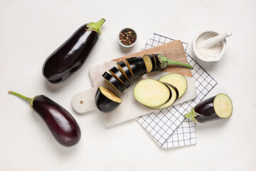 Naklejka premium Composition with cut fresh eggplants, cutting board and napkin on white background