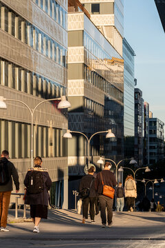 Stockholm Sweden city street scene with commuters pedestrians and traffic along urban sidewalk beside modern architecture during busy workday