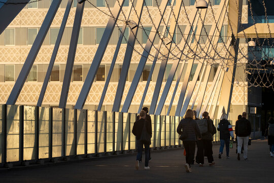 Modern Stockholm Sweden city urban walkway with pedestrians and commuters passing glass architecture creating layered silhouettes and civic energy