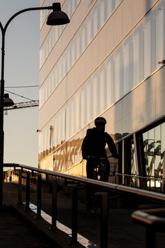 Modern Stockholm Sweden city architecture with glass ramp as cyclist meets pedestrian in urban commute moment framed by clean lines
