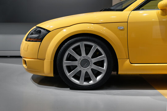 Close up side view of yellow Audi TT in parking garage: front wheel, fender, bumper and headlight. Berlin, Germany - January 16 2026