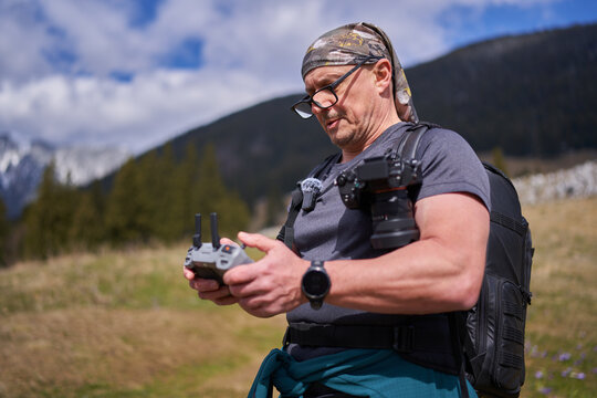 Man focused on drone controller in mountains