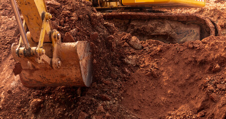 Backhoe working by digging soil at construction site. Bucket of backhoe digging soil. Crawler excavator digging on dirt. Excavating machine. Earth moving machine. Excavation vehicle. Trenching machine © Fahroni