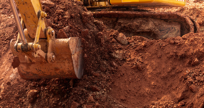 Backhoe working by digging soil at construction site. Bucket of backhoe digging soil. Crawler excavator digging on dirt. Excavating machine. Earth moving machine. Excavation vehicle. Trenching machine