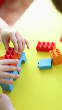 Close-up footage captures two kids' hands building with a construction set. They carefully place each piece, showcasing teamwork, problem-solving, and the excitement of creating something new.