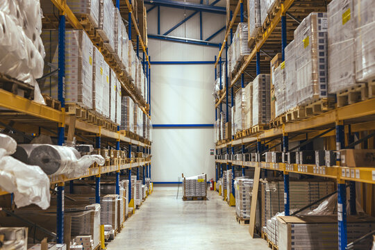 Large Industrial Warehouse Interior With Pallet Racking and Stacked Boxes In Aisle