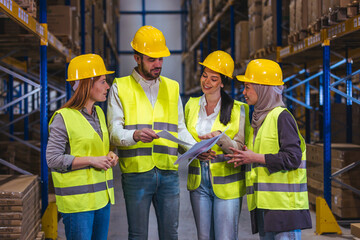 Warehouse Team Meeting With Safe Workers Wearing Hard Hats and High-Visibility Vests Reviewing...