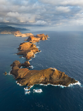 Aerial view of Ponta de Sao Lourenco peninsula with rugged volcanic cliffs and deep blue ocean under a cloudy sky in Canical, Madeira, Portugal.