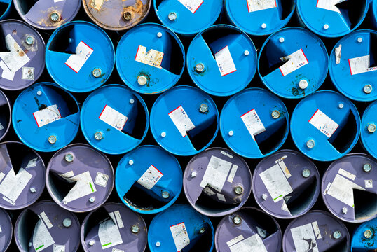 Old chemical barrels. Blue and purple oil drum. Steel oil tank. Toxic waste warehouse. Hazard chemical barrel with warning label. Industrial waste in metal drum. Hazard waste storage in factory.