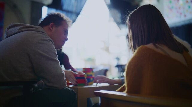 Young students with a disability play a colorful block-stacking game. They are focused on the interactive activity together.