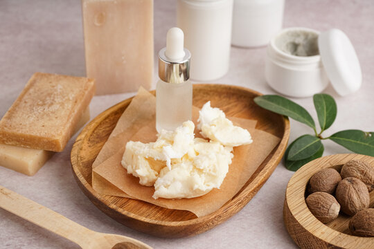Composition with plate of shea butter, nuts and cosmetic products on light background
