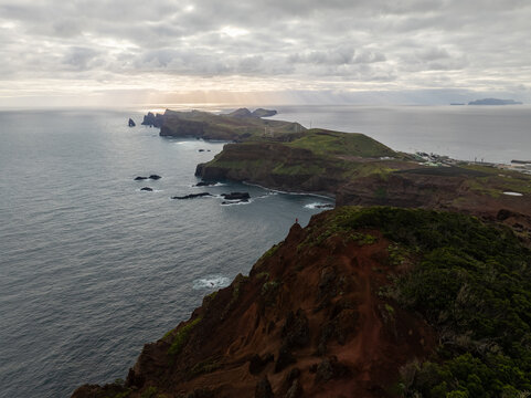 Aerial view of Ponta de Sao Lourenco with its dramatic cliffs, green slopes, and rocky outcrops meeting the Atlantic Ocean under a cloudy sky in Canical, Madeira, Portugal.