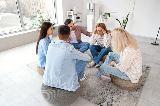 Support group session with stressed woman receiving comfort from therapist and participants in modern counseling office, mental health therapy, addiction recovery and emotional support
