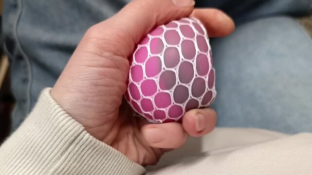 The process of interacting with an anti-stress toy: squeezing a mesh ball by hand
