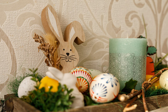 Close-up of Easter decoration with a wooden bunny, decorated eggs and a green candle, spr