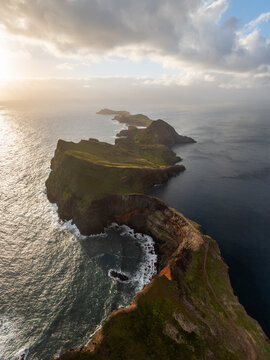 Aerial view of Ponta de Sao Lourenco peninsula with rugged cliffs and ocean waves under a dramatic cloudy sky in Canical, Madeira, Portugal.