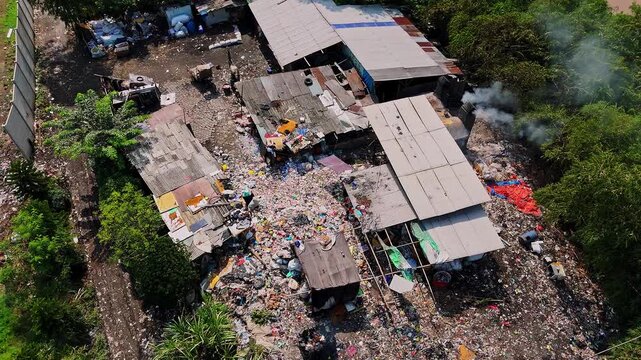 Aerial view of massive plastic waste pile accumulating around informal settlements and makeshift shelters