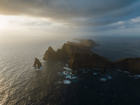 Aerial view of the rugged cliffs of Ponta de Sao Lourenco jutting into the dark ocean under a dramatic cloudy sky in Canical, Madeira, Portugal.