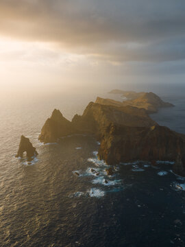 Aerial view of the dramatic cliffs of Ponta de Sao Lourenco with waves crashing against the rugged coastline during golden hour Canical, Madeira, Portugal.