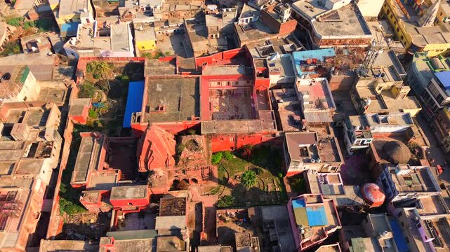 High-angle drone shot of the historic red sandstone Radha Madan Mohan Hindu temple surrounded by the traditional urban landscape of Vrindavan, India.