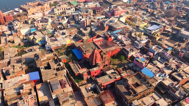 A high-angle drone shot capturing the iconic red sandstone architecture of the Radha Madan Mohan Temple amidst the dense urban landscape of Vrindavan, Uttar Pradesh.
