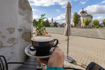 Cappuccino cup with heart latte art in Zhovkva city square view