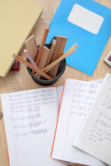 Fototapeta premium Open copybooks with math formulas and stationery on wooden table