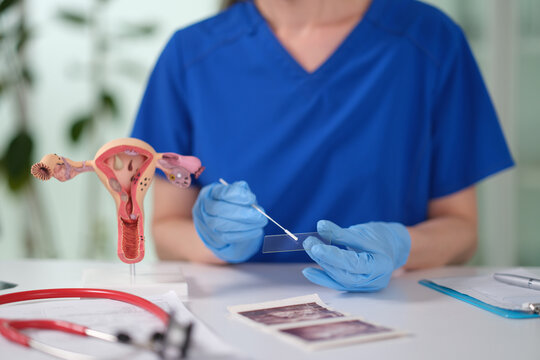 A healthcare worker in blue scrubs prepares a slide for testing while surrounded by medical tools and diagrams. This scene captures the essence of diligent care during patient examinations.